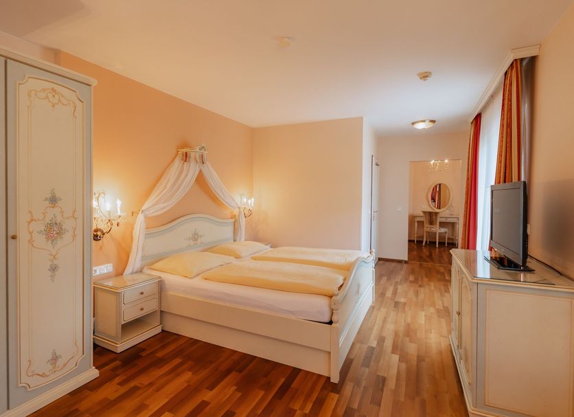 Schlössl Hotel Kindl in Bad Gleichenberg guest room with double bed, wardrobe, TV and wood flooring