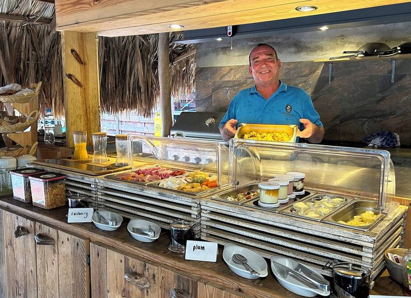 Buffet station at Sonrisa Boutique Hotel - Adults Only in Kralendijk with a smiling staff member serving food