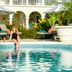 Coral Reef Club in Holetown, woman sitting at pool edge by tropical lounge chairs