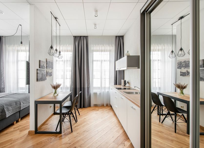 Piano Apartments in Kaunas studio with bed, dining table, kitchenette and mirrored wardrobe