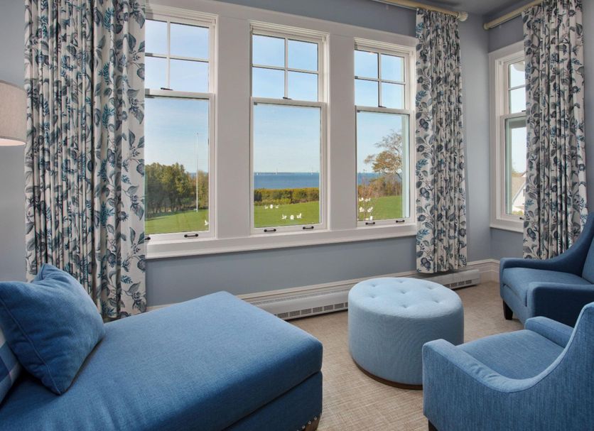 The Inn at Stonecliffe, Mackinac Island: guest room with blue seating and large windows overlooking lawn and water.