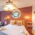 Bhoma Bourges - Hôtel room with king bed, sofa, large window, and round mirror in Bourges