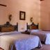 Hotel del Vasco in Zacatecas room with two beds, open doorway, and warm traditional decor