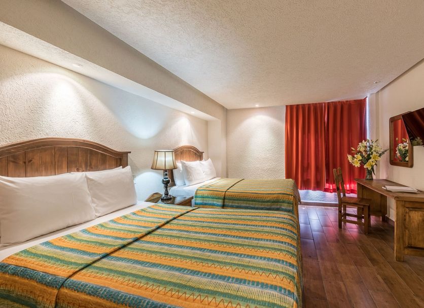 Hotel Abadia Tradicional Guanajuato room with two beds, wood floor, and red curtains