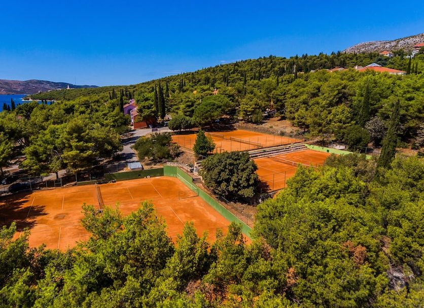 Hotel Medena in Seget Donji with outdoor clay tennis courts amid pine trees and sea view