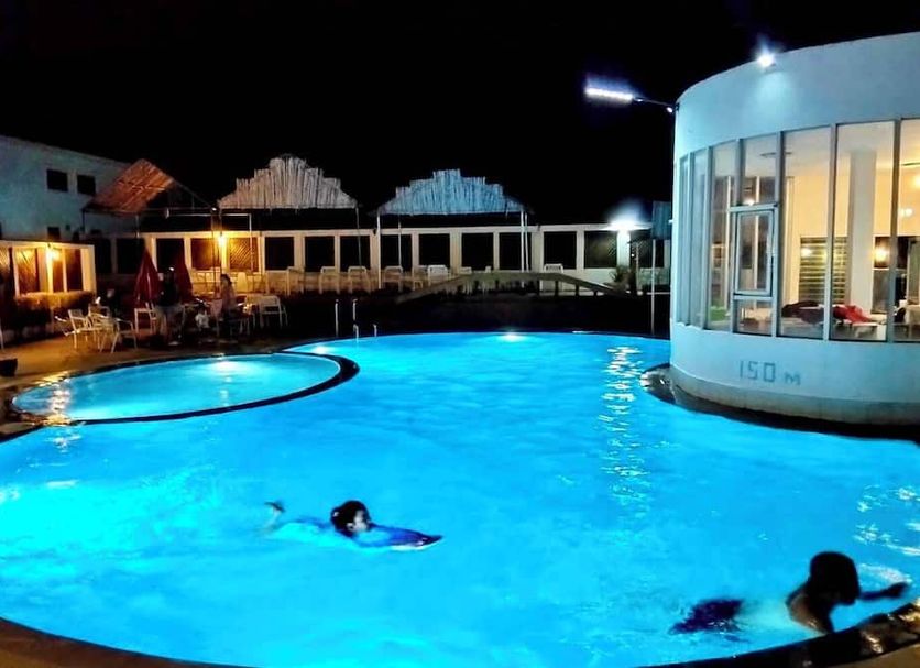 River City Hotel in Mukdahan featuring a lit outdoor pool at night with swimmers
