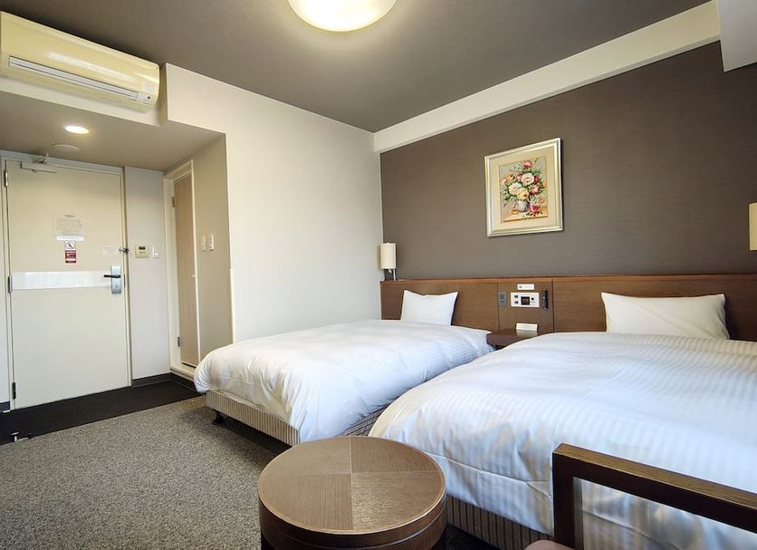 Hotel Route-Inn Iwakiizumi Ekimae guest room with two twin beds and entry door in Iwaki