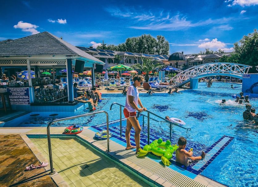 Hotel Silver in Hajdúszoboszló: outdoor pool with swimmers, bridge, and poolside seating