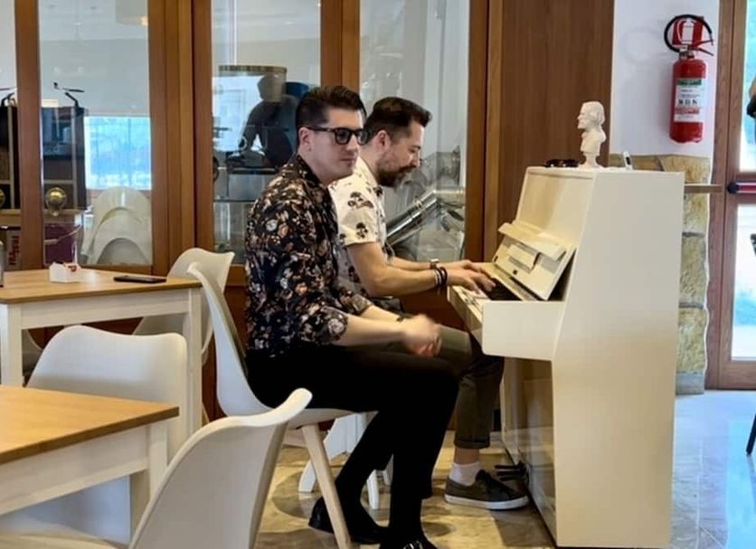 Hotel La Vetta Europa in Castellana Grotte: two men playing a white upright piano in lounge