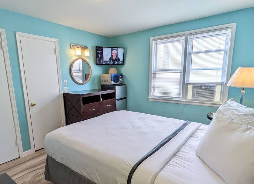 Clarem Happy Days Wildwood guest room with bed, TV, mini fridge, and window air conditioner