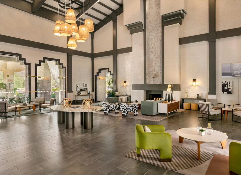 Hilton Scottsdale Resort & Villas lobby with high ceilings, hanging lights, fireplace seating and green chairs in Scottsdale