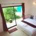 Phuket Airport Overnight Hotel room in Mai Khao with bed beside sliding glass door to garden patio