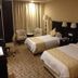 Xiang Ming Holiday Hotel in Huangshan guest room with two twin beds, chairs, and a floor lamp