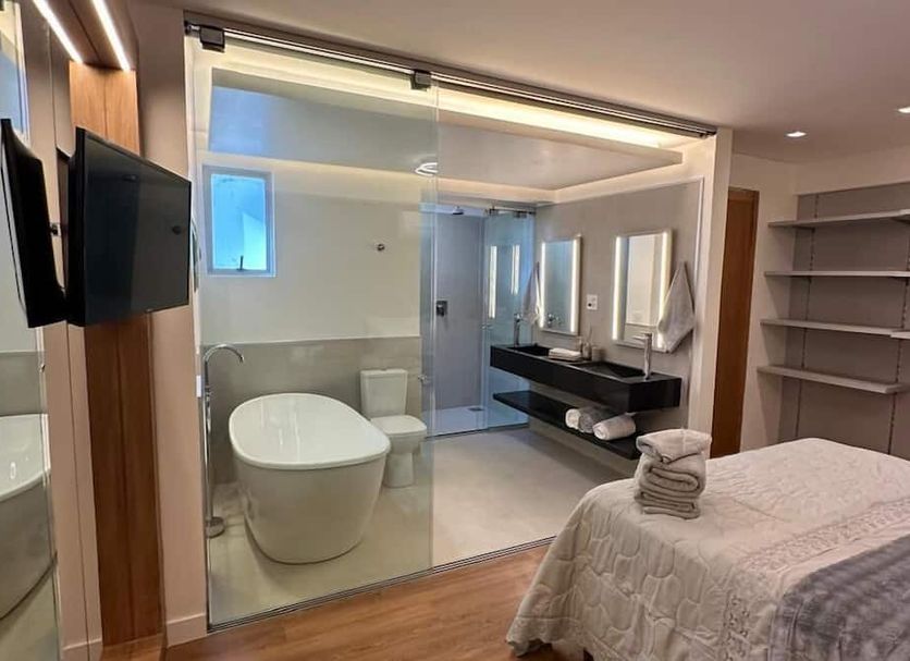 River Palace Hotel in Divinópolis guest room with glass wall bathroom, freestanding tub and shower