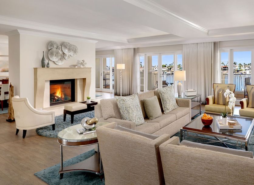 Balboa Bay Resort Newport Beach suite with fireplace, seating area and bay view through large windows