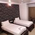 Hotel Naivedya, Aurangabad: twin beds, curtains, small table and chairs in a simple guest room