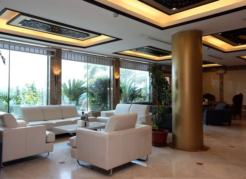 Jazan Inn Hotel lobby lounge in Jazan with white armchairs, sofas, palm views, and gold columns