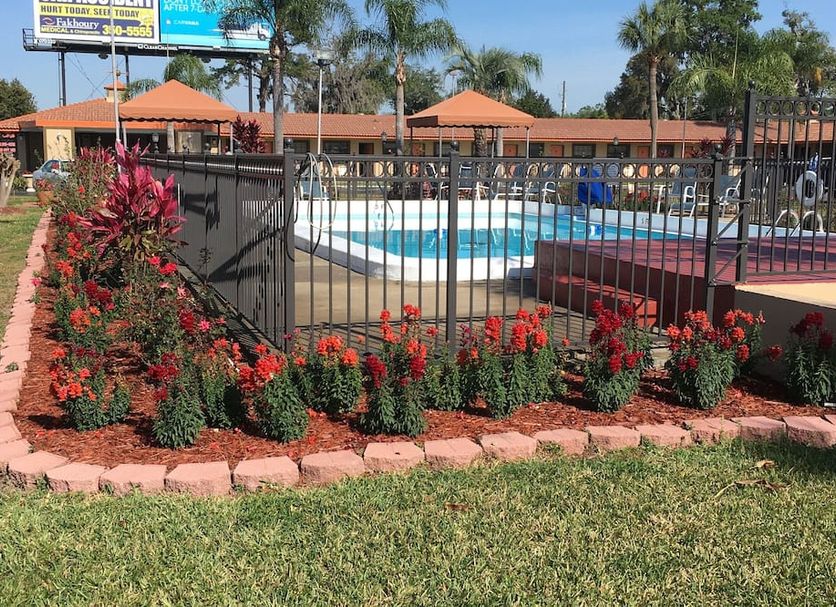 Silver Princess Motel in Ocala with outdoor pool, black fence, red flowers, and orange umbrellas