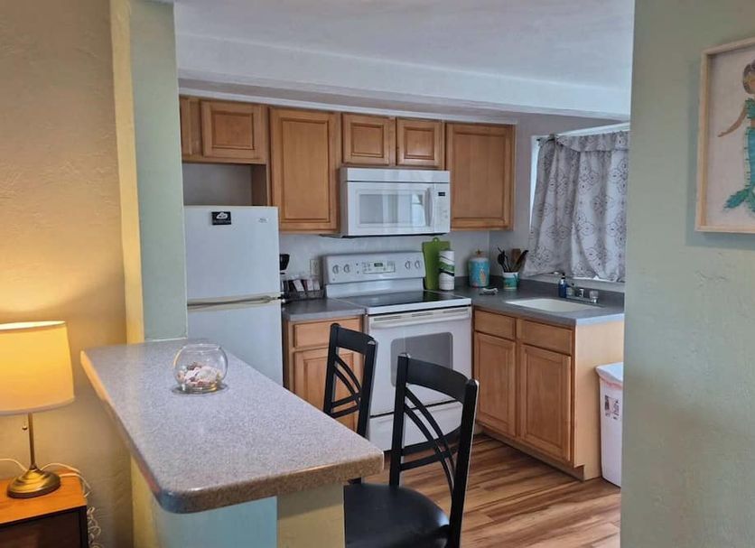 Studio 1 Motel in Daytona Beach kitchenette with white appliances, wood cabinets, breakfast bar and chairs