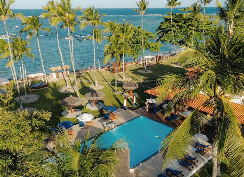 Pousada Caeira in Morro de Sao Paulo with ocean-view pool, palm trees, and beach loungers
