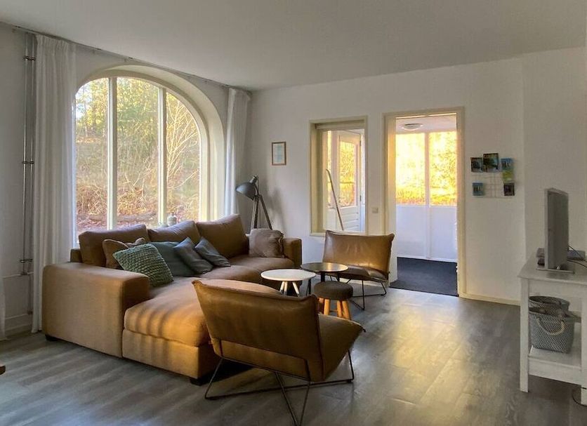 Landgoed Huize Glory in Bergen aan Zee living room with large arched window and seating area