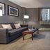 Hotel Faubourg Montreal guest room with sofa, armchair, coffee table and city-view window