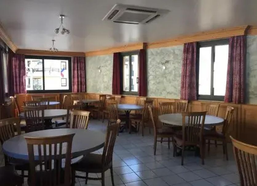 Hotel Le Centre in Brides-les-Bains dining room with round tables, wooden chairs, and curtained windows