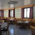 Hotel Le Centre in Brides-les-Bains dining room with round tables, wooden chairs, and curtained windows