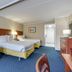 The Spinnaker in Ocean City guest room with two beds, blue sofa, and desk