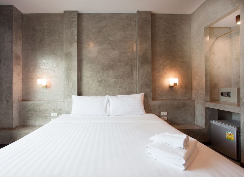 Ritsurin Boutique Hotel in Phuket City guest room with double bed, concrete walls and bedside lights