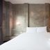 Ritsurin Boutique Hotel in Phuket City guest room with double bed, concrete walls and bedside lights