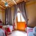 Kasbah Tizzarouine in Boumalne Dadès: twin beds, rustic ceiling, curtains, and a wood door to balcony
