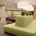 Home2 Suites by Hilton Idaho Falls lobby seating area with tables, chairs, and green banquette seating