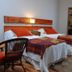 Rio Arriba Suites Apartments y Resto in Bella Vista, twin beds with orange pillows and woven chair in guest room