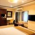 The Cabin Hotel in Accra guest room with bed, desk, wardrobe, TV, sofa, and window curtains