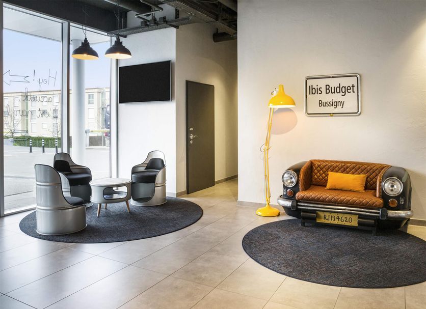 Ibis Budget Lausanne Bussigny lobby with seating area, floor lamp, and vintage car-style sofa