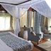 Great Rift Valley Lodge and Golf Resort in Naivasha guest room with four-poster bed and armchairs