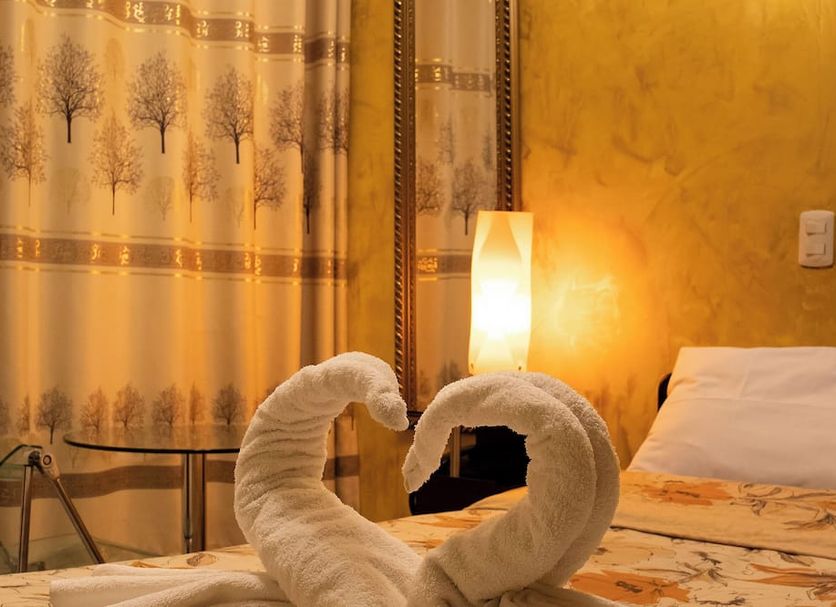 Tambo del Solar, Arequipa: bed with swan towel art, bedside lamp, and warm yellow room interior