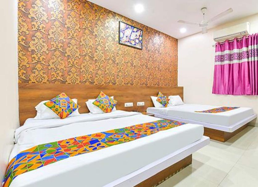 Fabhotel Raghumani Palace, Ujjain: bright twin-bedded hotel room with patterned wall and pink curtains