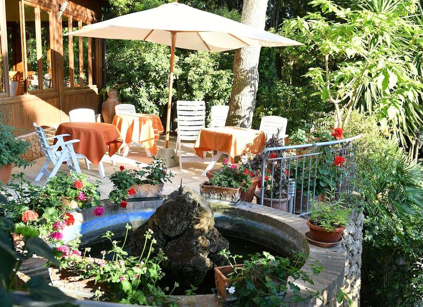 Hotel Rosa Del Tirreno in Quercianella garden terrace with tables, umbrella, and small decorative pond