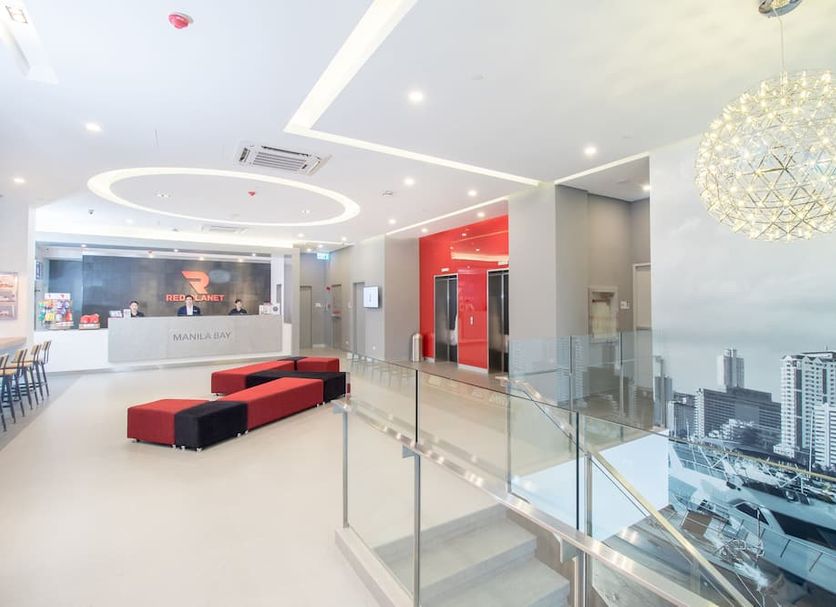 Red Planet Manila Bay lobby in Manila with modern seating, glass railing, and city mural