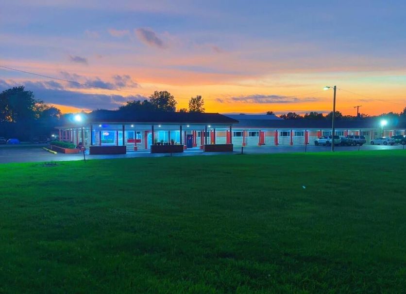 Catalina Airport Motel in Indianapolis at sunset with lit motel buildings and a large green lawn