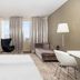 Zijin Hotel Belgrade room with twin beds, black chair, sofa, desk, and floor-to-ceiling window view