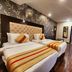 Housez 43 Kolkata hotel room with two single beds, patterned accent wall, and wood flooring