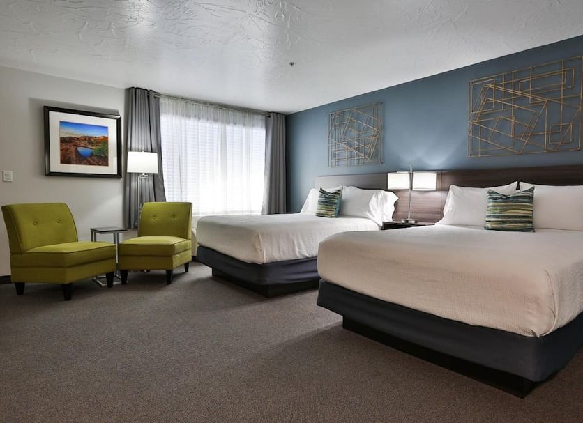 The Chalet in Saint George guest room with two queen beds, armchairs, floor lamp, and window with sheer curtains