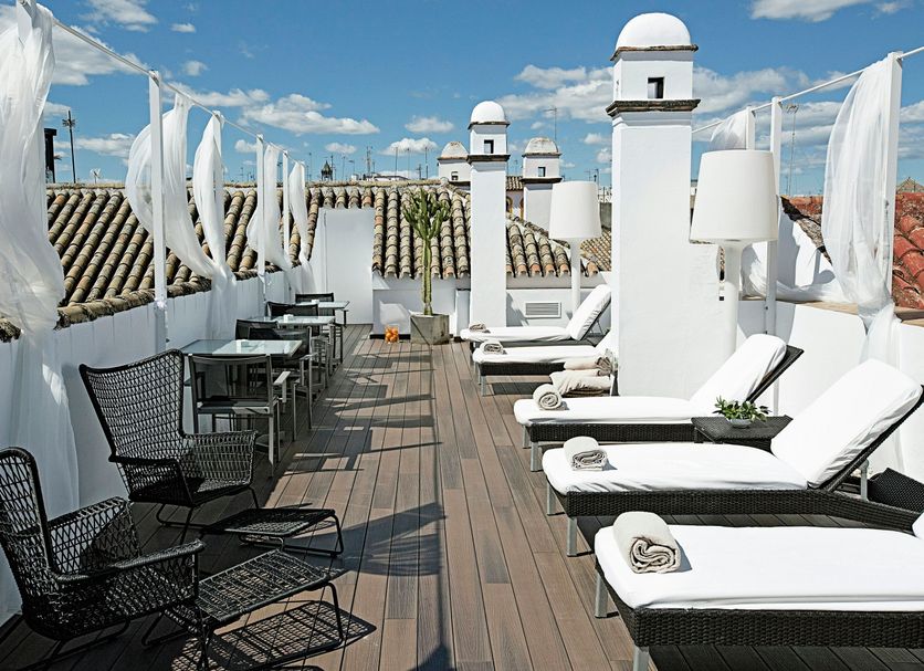 Rooftop terrace at Hospes Las Casas del Rey de Baeza in Seville with loungers, tables and city views