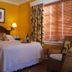 Colony Hotel & Cabana Club guest room in Delray Beach with king bed, bedside lamps, and window blinds