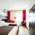 Bastion Hotel Zoetermeer room with two beds, red curtains, and a black chair in Zoetermeer