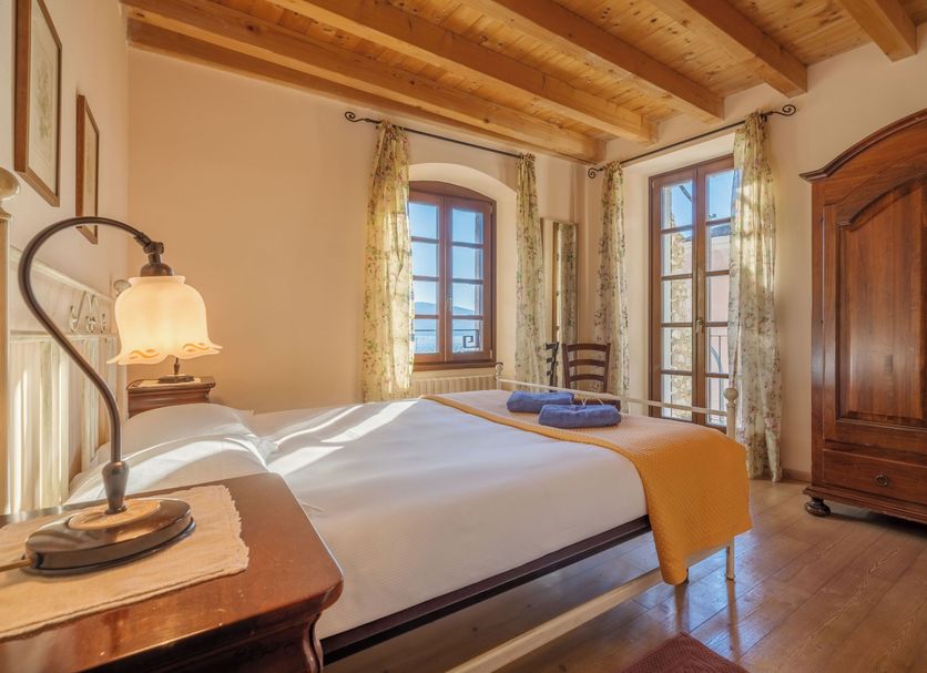 Residence Fondo La Campagnola room in Gargnano with wooden beams, double bed, and armoire