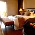 Velmore Hotel & Spa in Pretoria guest room with king bed, bedside lamps, bench and flower arrangement